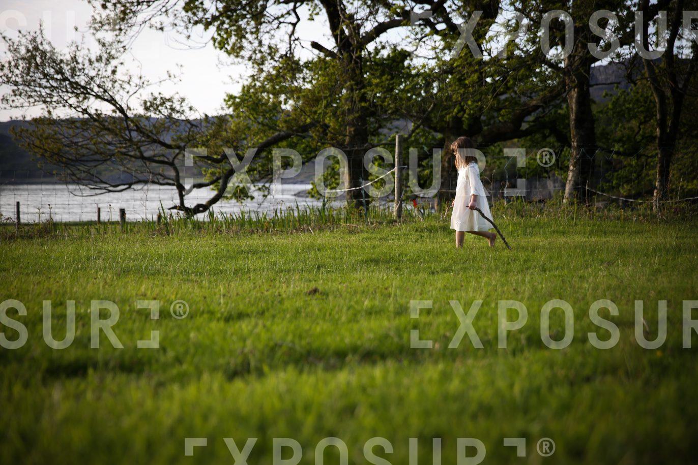 Girl walking through field in the evening sun