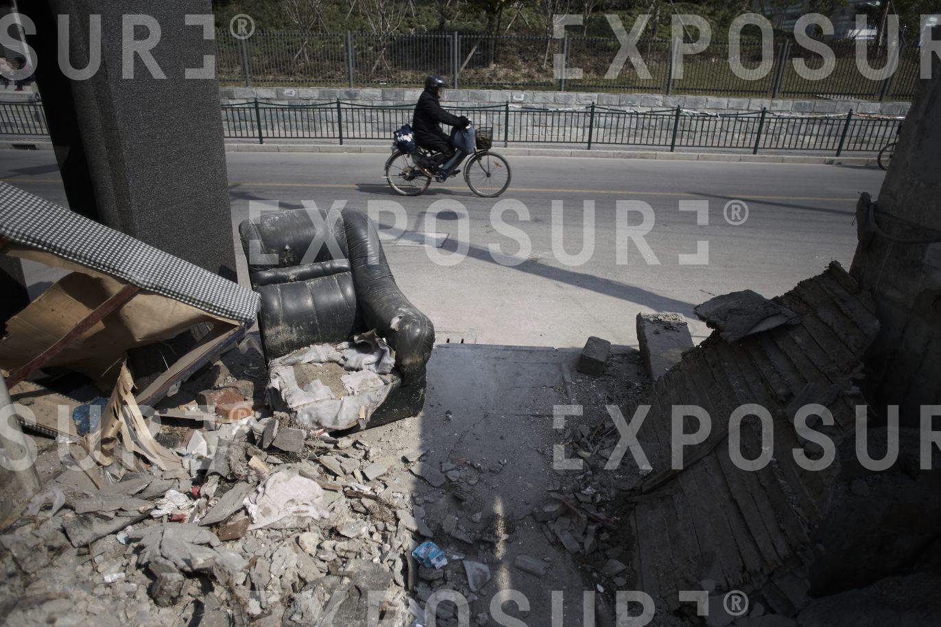 Cyclist passing demolished building, Shanghai